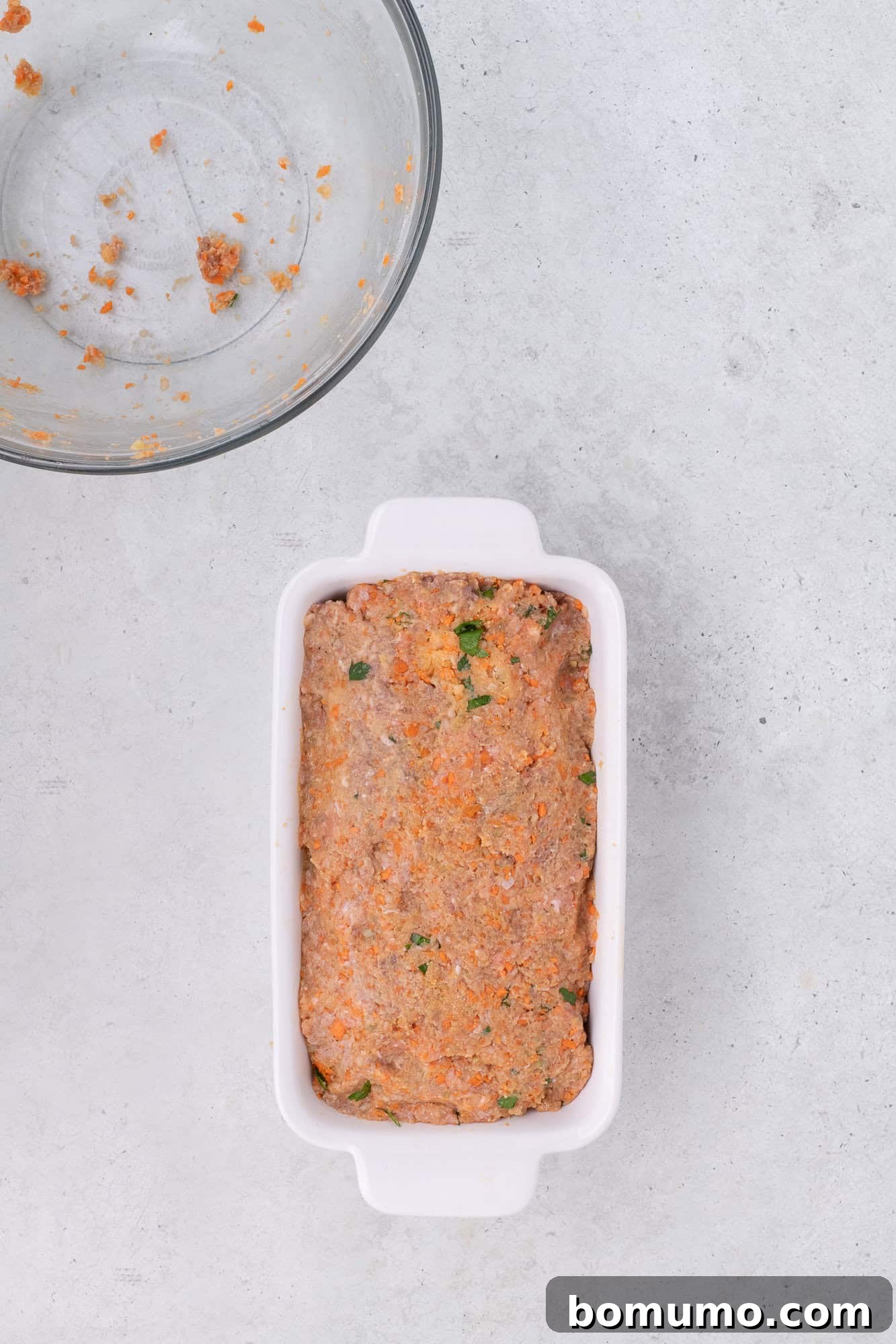 Unbaked meatloaf mixture neatly shaped and pressed into a loaf pan.