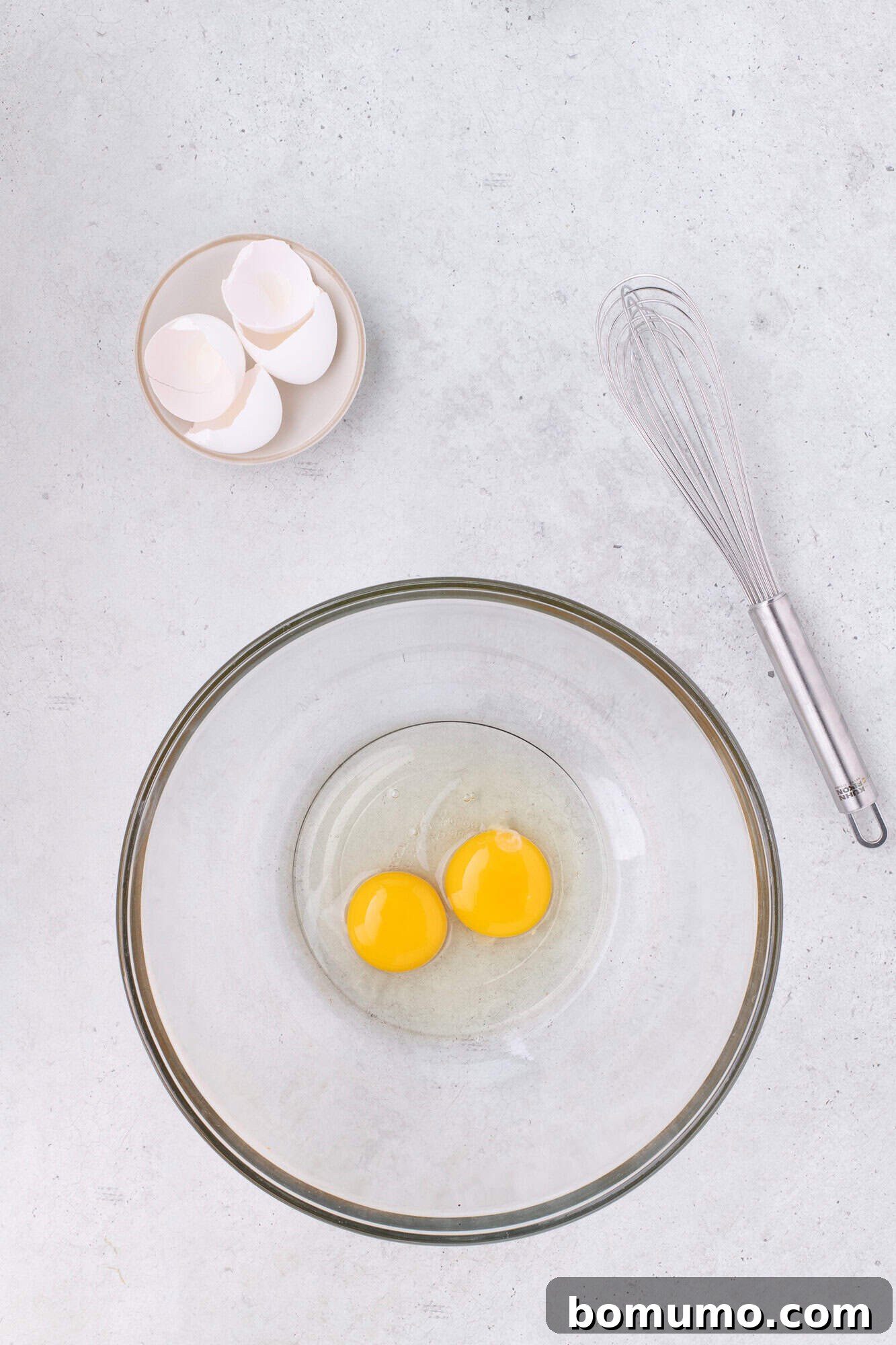 Fresh eggs cracked into a large mixing bowl, ready to be beaten.