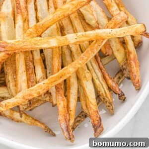 Close up of perfectly crispy french fries in a white ceramic dish.