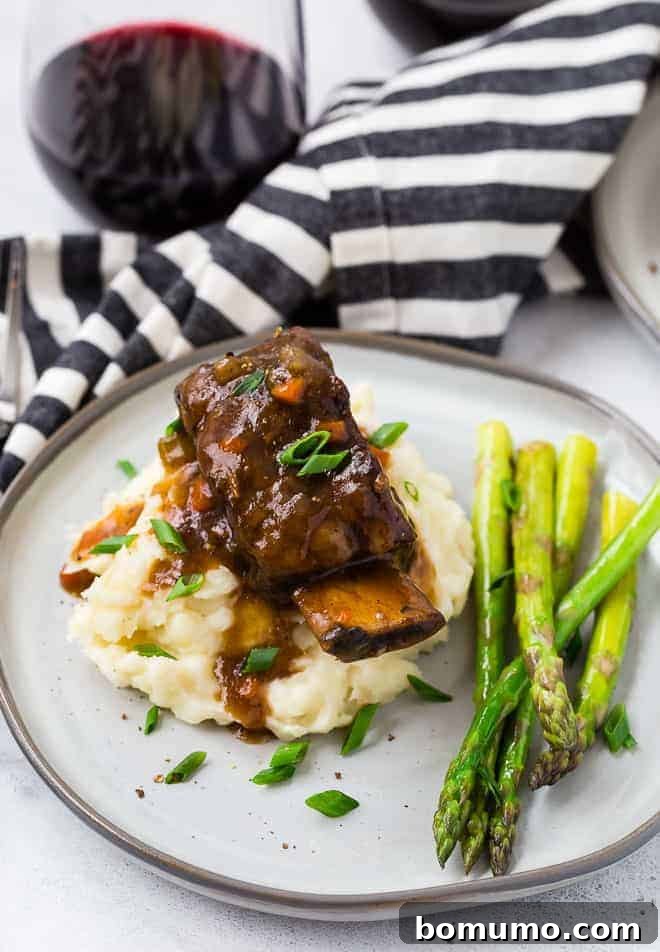Image of short ribs cooked in an instant pot pressure cooker. Asparagus, mashed potatoes, and red wine are also pictured. 
