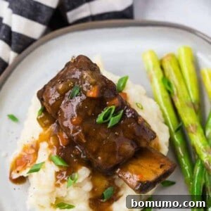 Image of a cooked short rib and gravy atop a pile of creamy mashed potatoes.