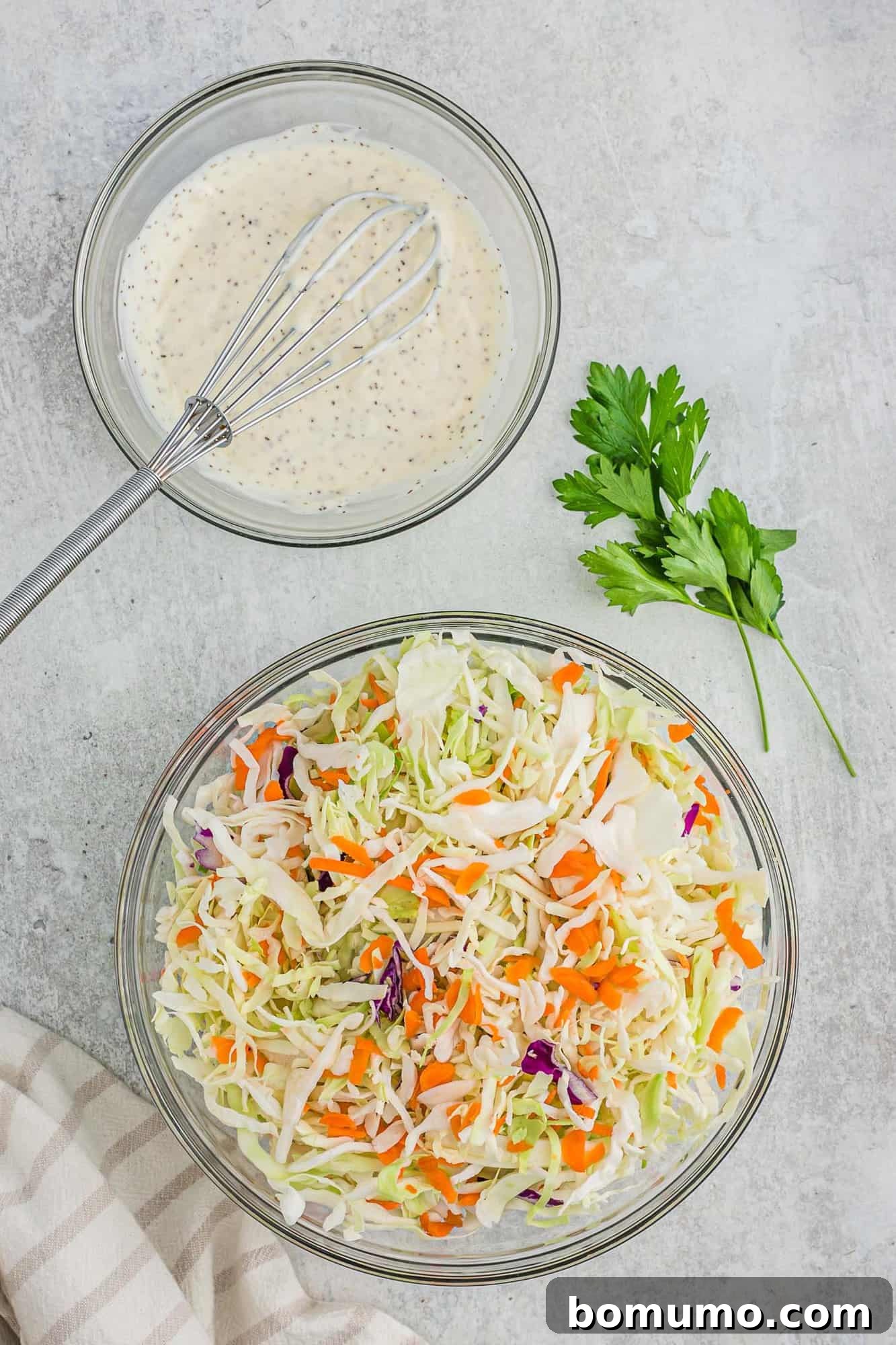 Shredded cabbage in one bowl, freshly mixed coleslaw dressing in another.