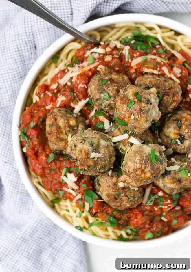 Image of a bowl of turkey meatballs on top of spaghetti and spaghetti sauce. 