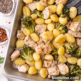 A baking tray filled with golden-brown gnocchi, vibrant broccoli florets, and seasoned chicken pieces, promising a satisfying meal.