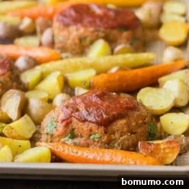 Mini meatloaves and roasted vegetables on a sheet pan, forming a complete dinner.