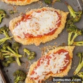 Overhead of golden-brown chicken Parmesan with vibrant broccoli on a sheet pan, ready to serve.