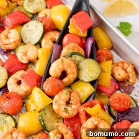Pan of roasted shrimp with a mix of colorful vegetables including zucchini, bell peppers, cherry tomatoes, and red onions.