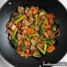 Beef and vegetable stir fry in a black wok.