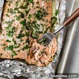 Grilled salmon in foil, topped with chives, offering an easy cleanup solution.