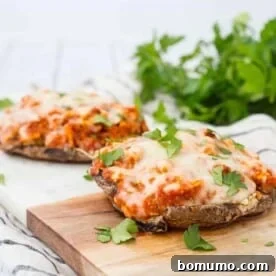 Two servings of stuffed mushrooms on cutting board, garnished with chopped parsley.