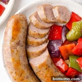 Baked Italian sausage with peppers and onions, partially sliced, a simple and flavorful meal.