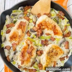 Overhead of chicken with sauce in orange skillet, garnished with bacon.