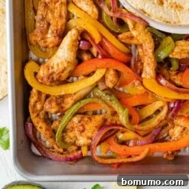 Overhead view of sheet pan fajitas with chicken, peppers, and onions.