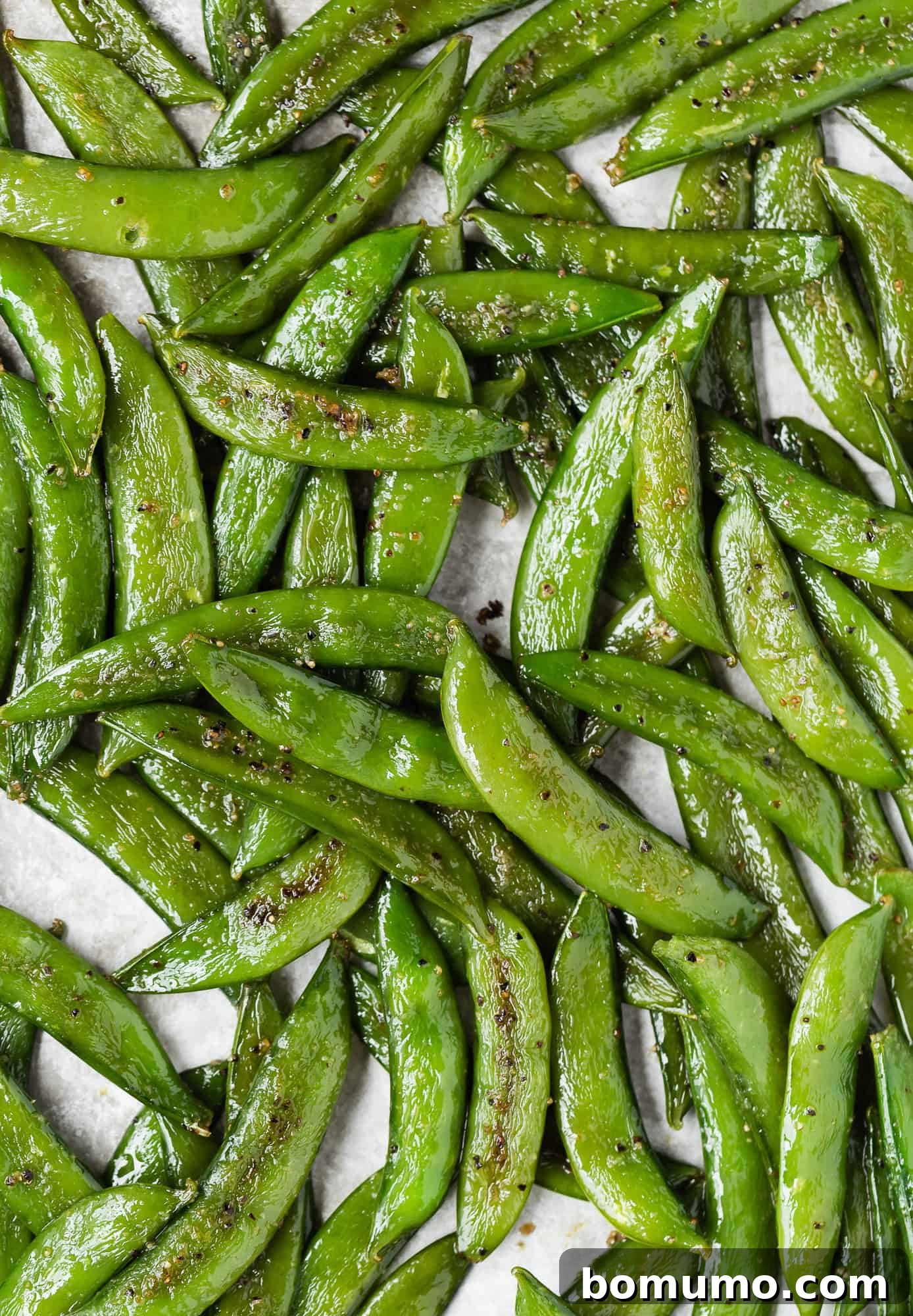 Crispy Roasted Sugar Snap Peas 2 Close up view of sugar snap peas on a pan, beautifully caramelized.