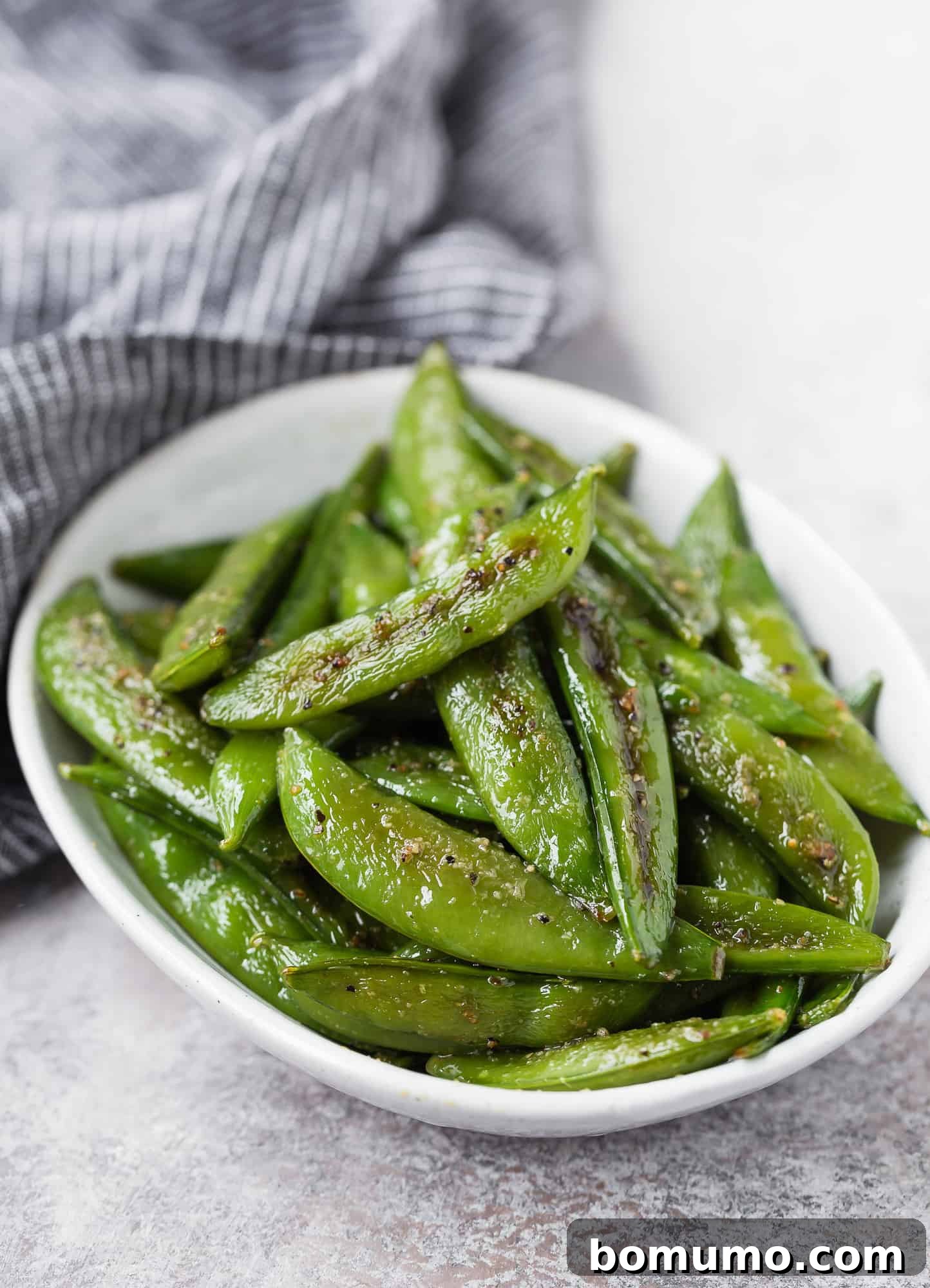 Crispy Roasted Sugar Snap Peas 3 Snap peas in a small white oval bowl, ready for preparation.