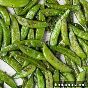 Crispy Roasted Sugar Snap Peas 8 Close up view of roasted sugar snap peas on a pan, illustrating the perfect golden-brown spots.