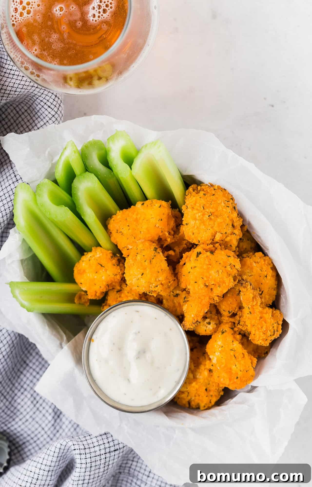 Overhead view of a generous platter of air fryer buffalo cauliflower bites, artfully arranged with fresh celery sticks and creamy dipping sauce.