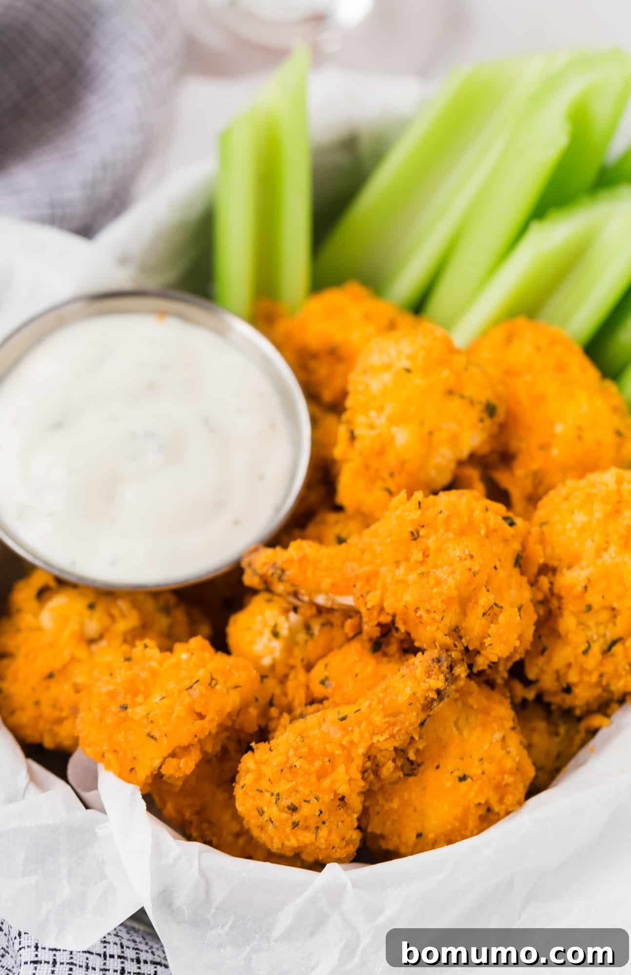 A vibrant plate of air fryer buffalo cauliflower bites, perfectly crisp and golden, accompanied by a small bowl of creamy dipping sauce.