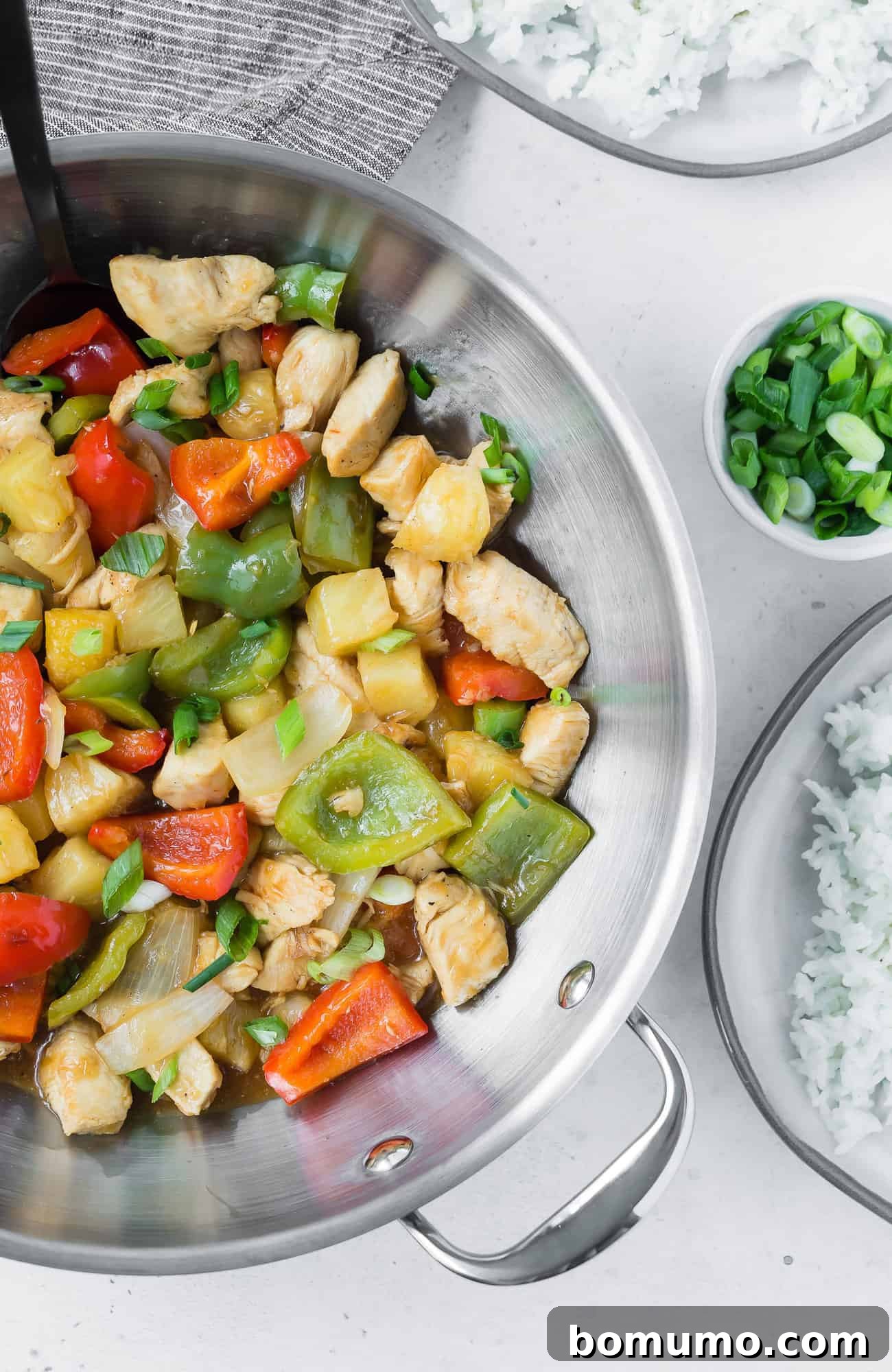 Chicken stir fry in a wok with peppers and pineapple.
