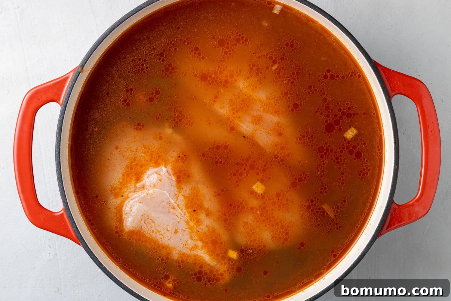 Raw chicken in a tomato based broth.