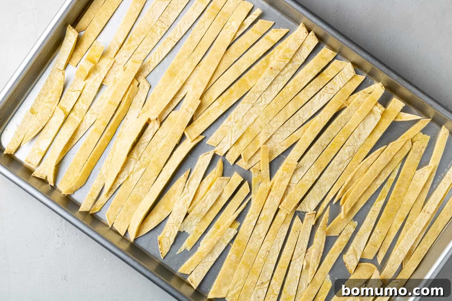 Tortilla strips on a baking sheet, not yet cooked.