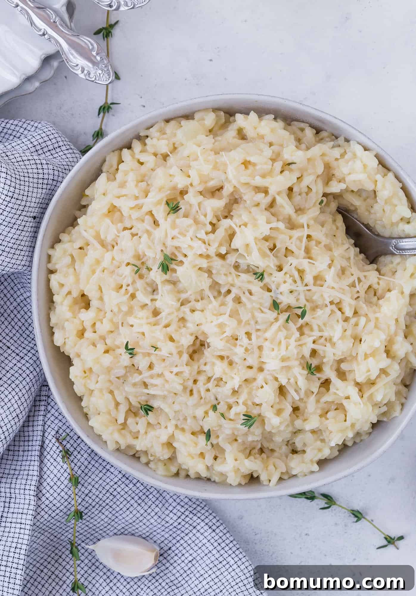 Bowl of instant pot risotto topped with parmesan cheese and fresh thyme.