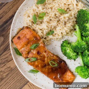 Soy glazed salmon on a plate with broccoli and rice, showcasing a perfectly cooked fillet with a rich, glossy glaze.