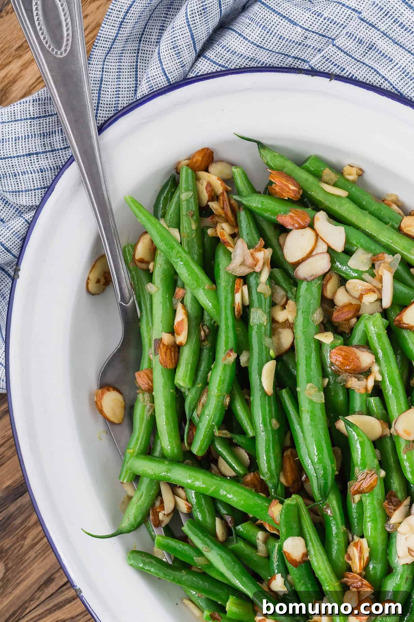 Exquisitely prepared Green Beans Almondine arranged on an elegant white platter, showcasing the golden-brown almonds and fresh green color of the beans.