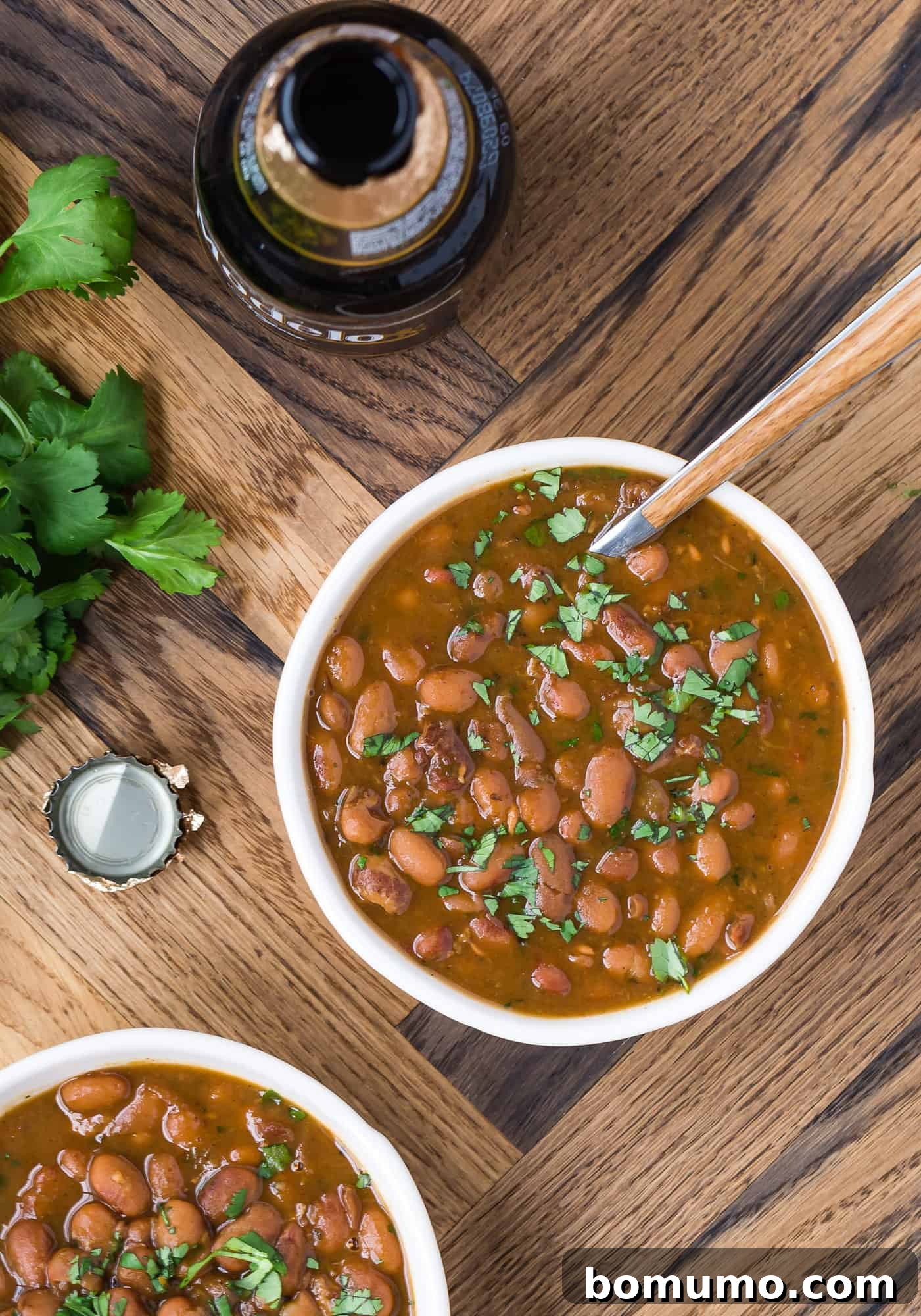Drunken beans in a white bowl with a spoon. 