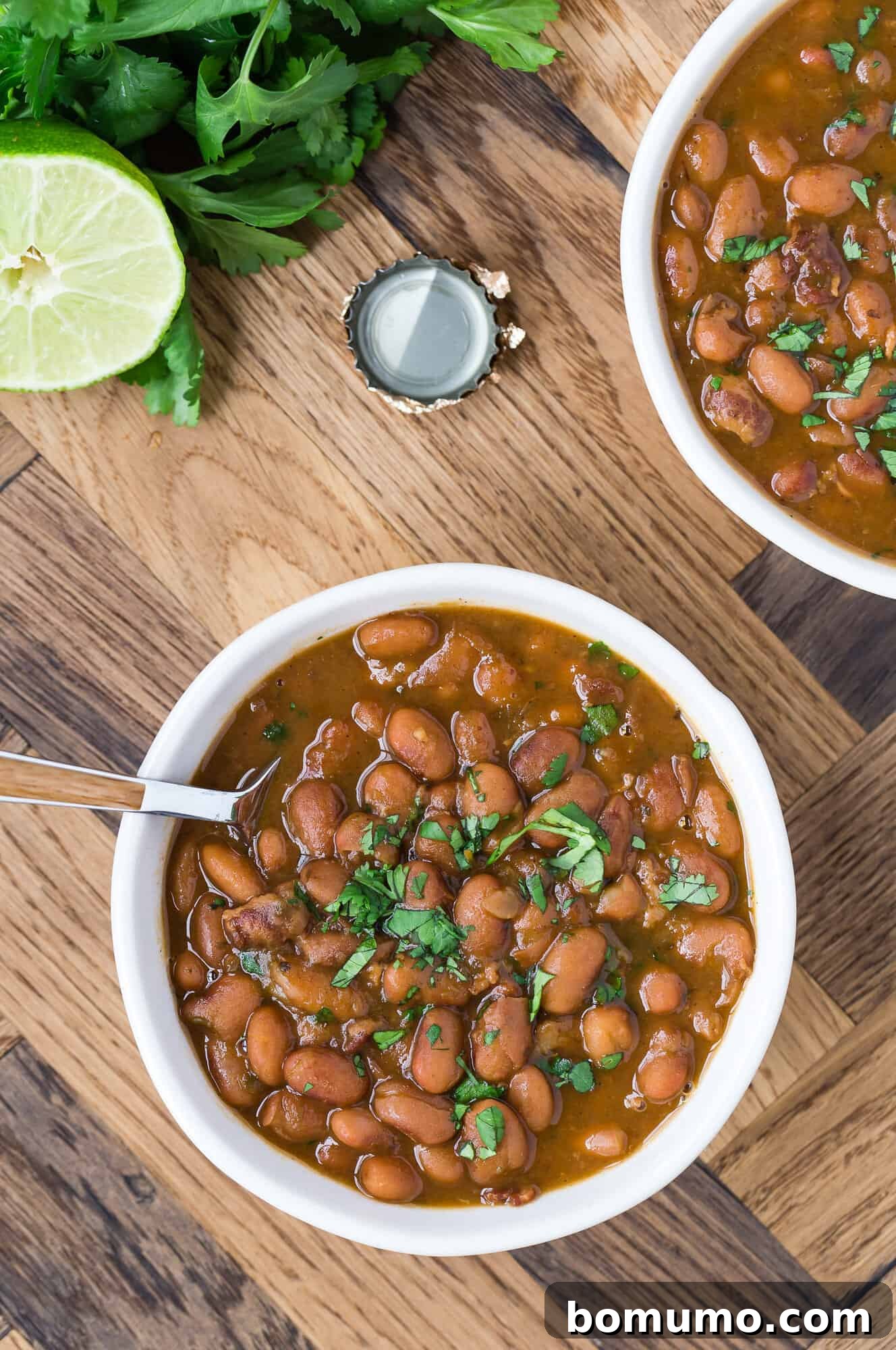 Two bowls of frijoles borrachos, garnished with cilantro.
