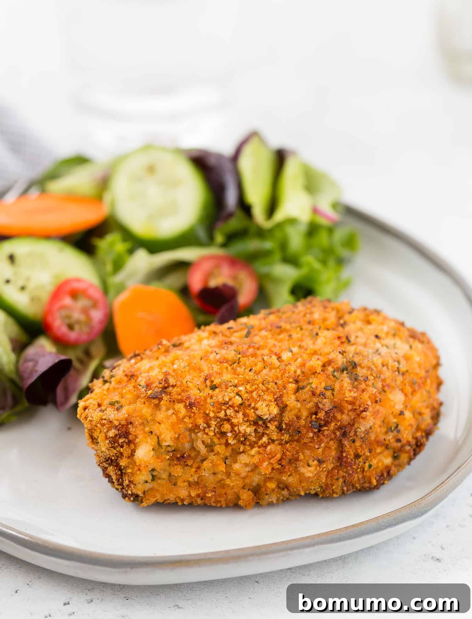 Air fryer breaded pork chop on a plate with a salad.