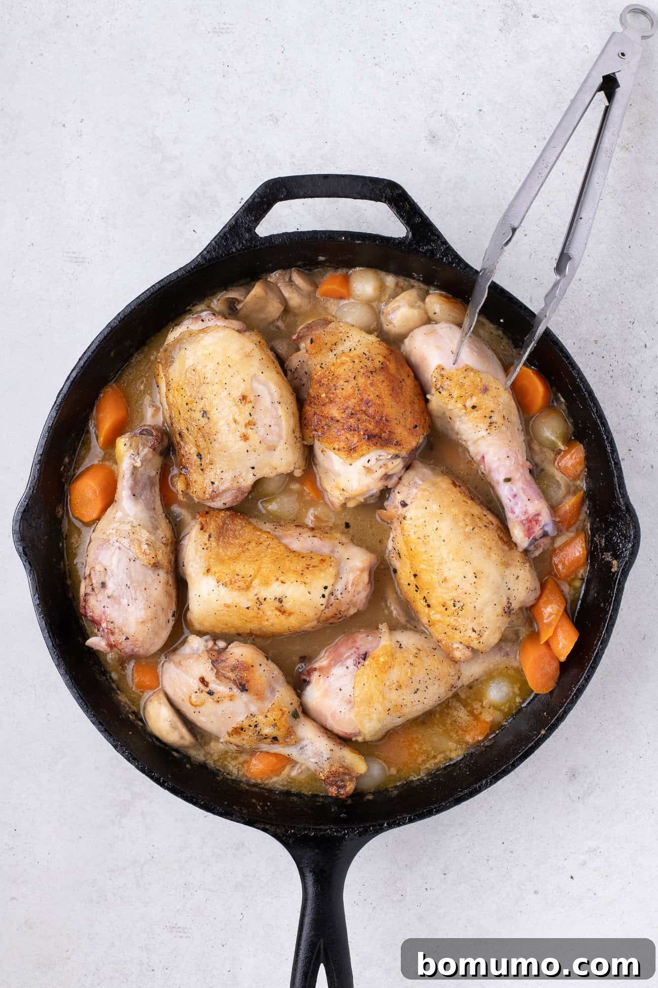Browned chicken pieces carefully placed back into the skillet, nestled within the creamy sauce and vegetables, ready for braising.