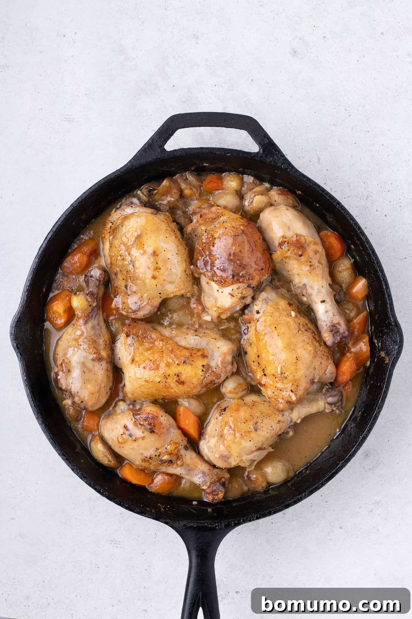 Cooked chicken pieces resting in the skillet after being removed from the oven.