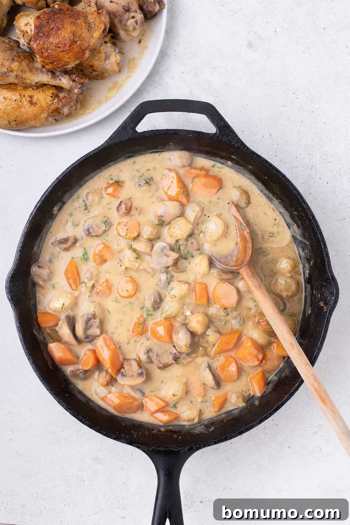 The heavy cream being gently stirred into the fricassee sauce, making it rich and smooth.