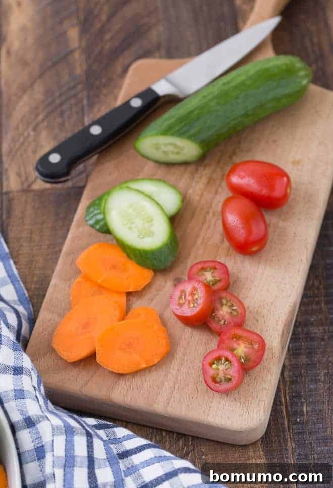 An assortment of sliced fresh vegetables for a salad, including bell peppers, cucumbers, and tomatoes, waiting to be dressed.