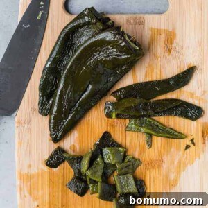 Image of roasted poblano peppers, two whole, one cut in a two different ways (strips, diced).