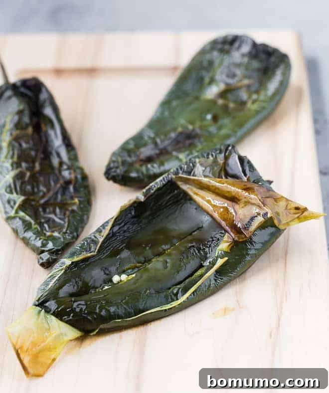Poblano Perfection: 4 Roasting Methods 4 Image of roasted poblano peppers, peelings beginning to be removed.