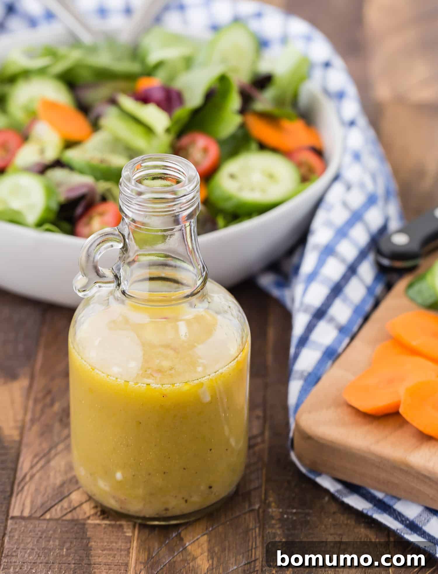 A close-up of a glass jar filled with golden white wine vinaigrette, ready to be shaken and served.