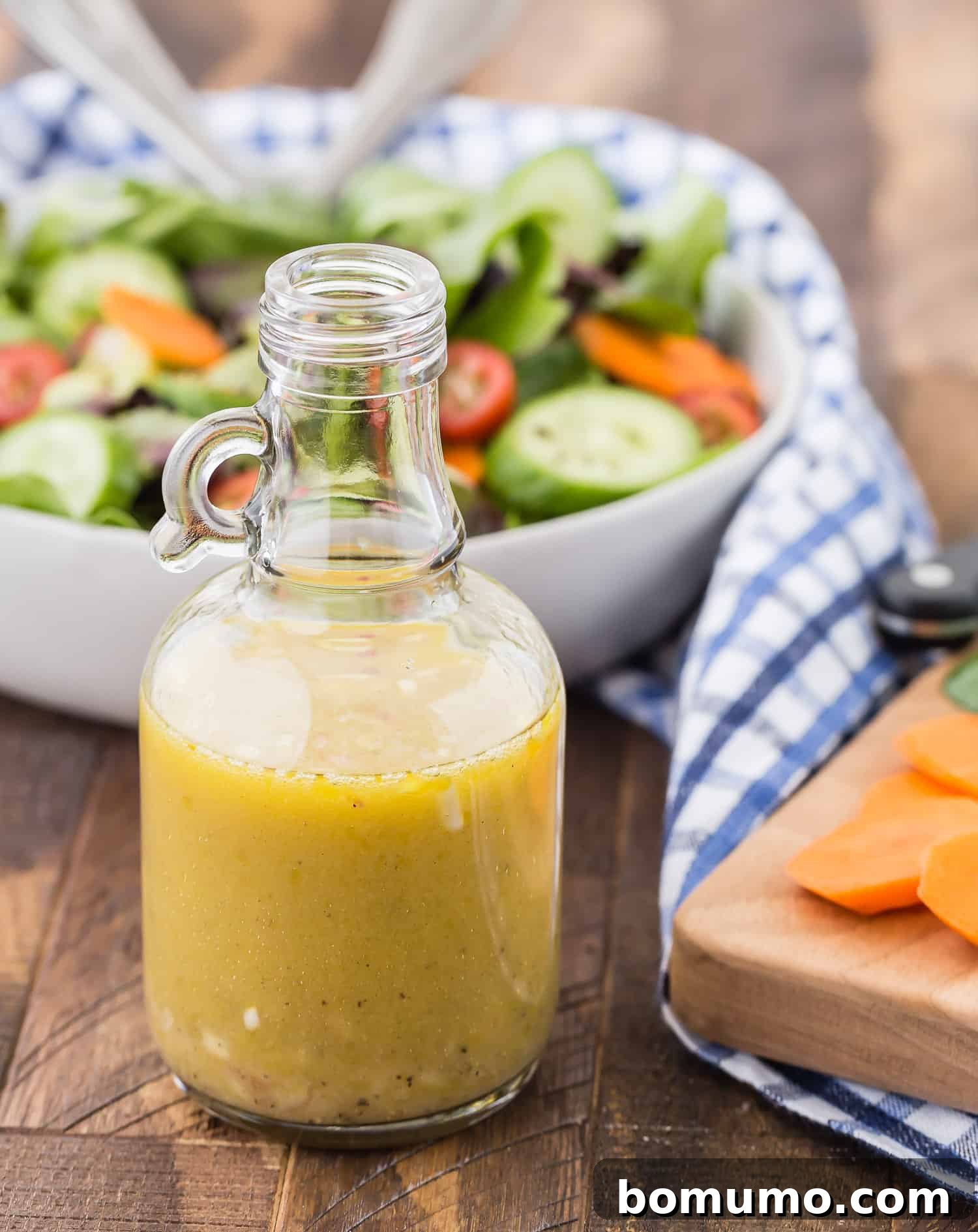 A small, clear glass jar filled with golden white wine vinaigrette rests on a white background, highlighting its pristine and inviting appearance.