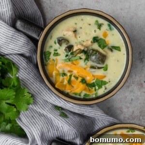 Overhead view of chile relleno soup, topped with cheddar cheese.