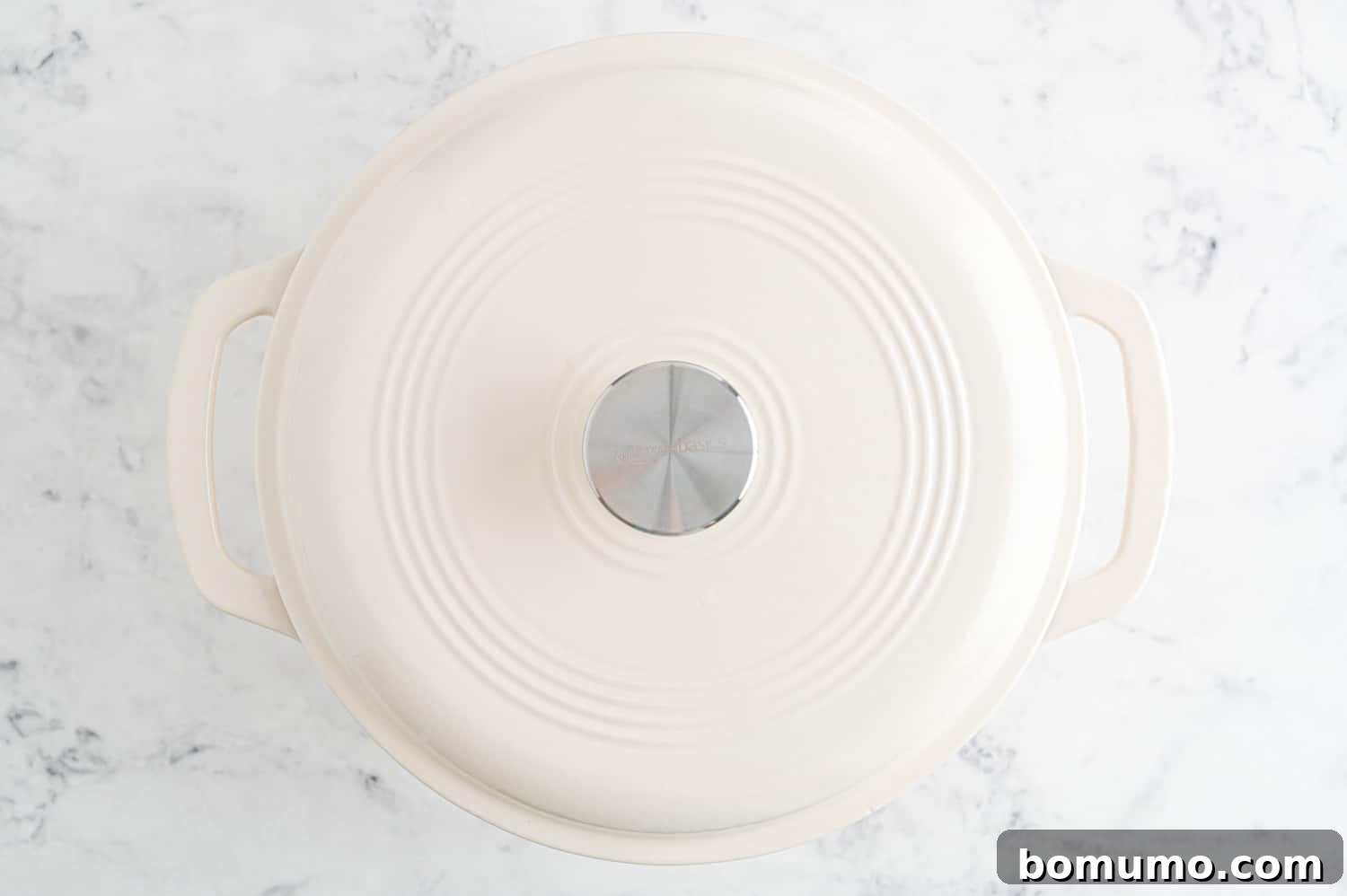 A covered pan on a stovetop, indicating the gentle simmering stage of poaching chicken.