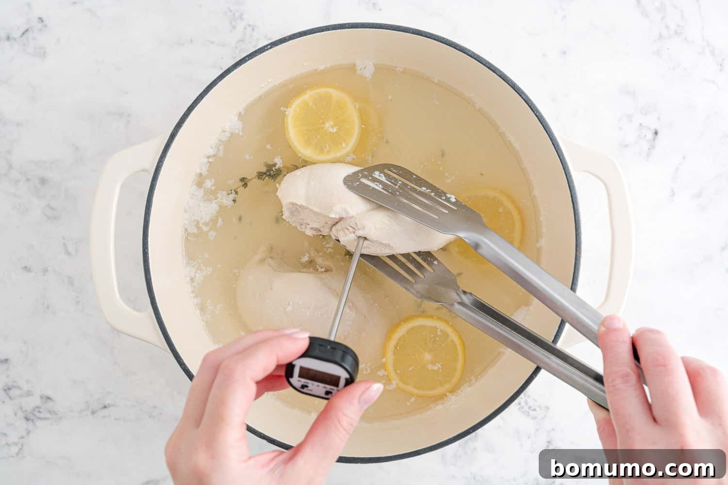 An instant-read thermometer being used to check the internal temperature of poached chicken in a pan.