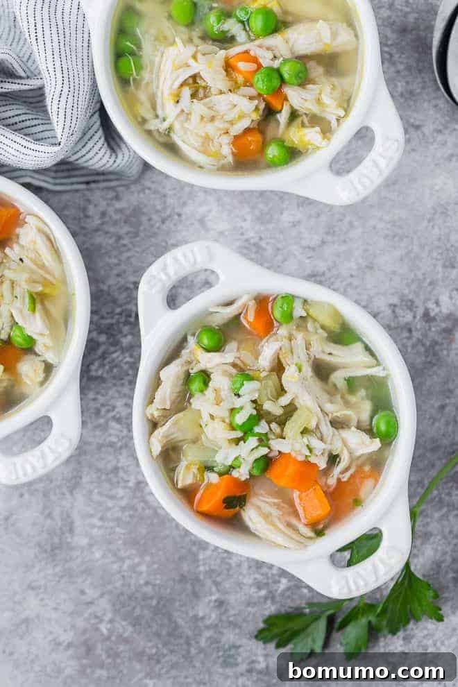 Three small glass white bowls full of chicken soup with rice and vegetables.