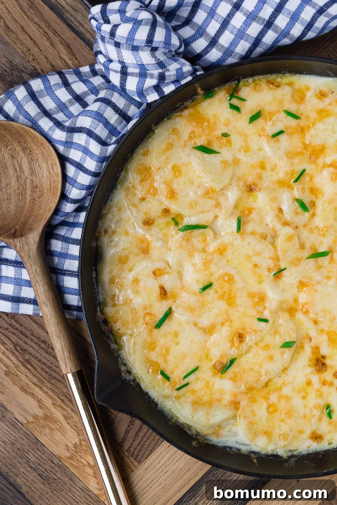 Overhead view of creamy, cheesy stovetop scalloped potatoes in a black pan, ready to be served.