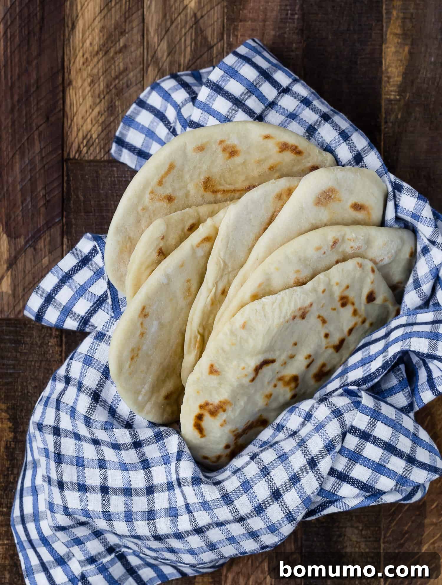 A charming collection of homemade flatbreads, artfully arranged in a rustic basket, highlighting their golden-brown spots and soft texture.