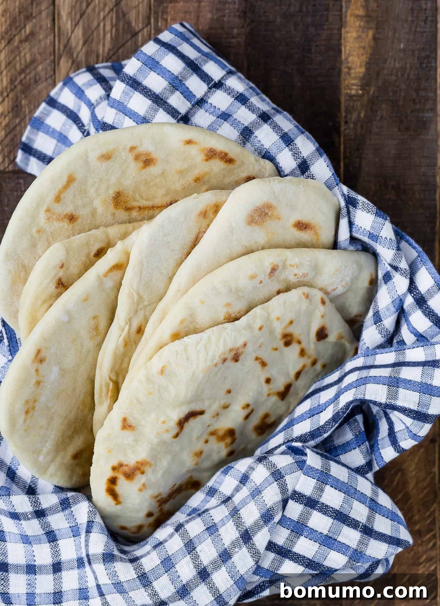 A stack of warm, pliable pita-like flatbreads nestled in a basket, showcasing their inviting texture and readiness for any meal.