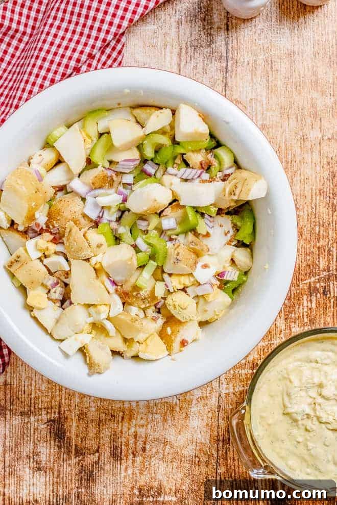 A bowl of potato salad ingredients being mixed together.
