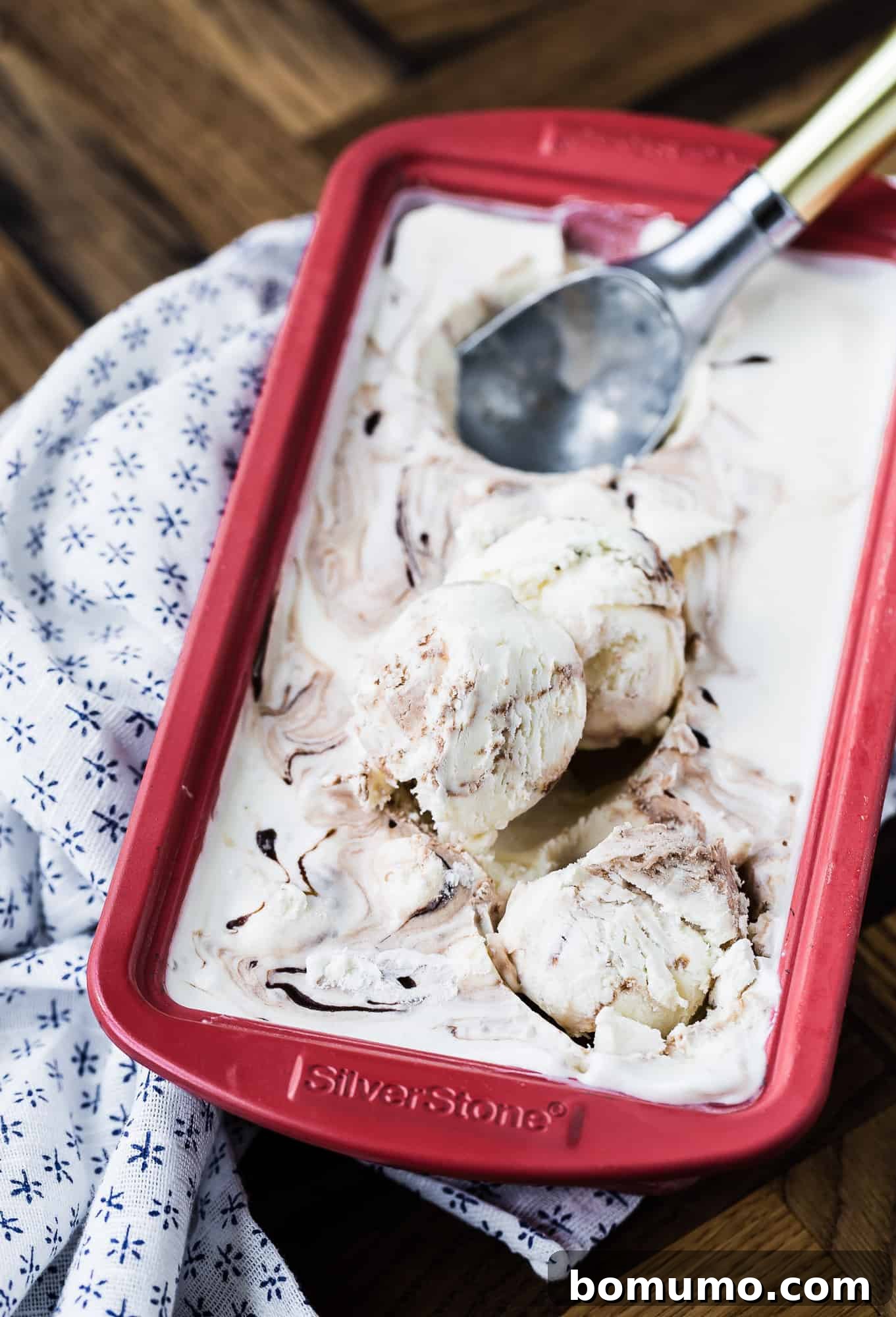 Ice cream in a red loaf pan being scooped.