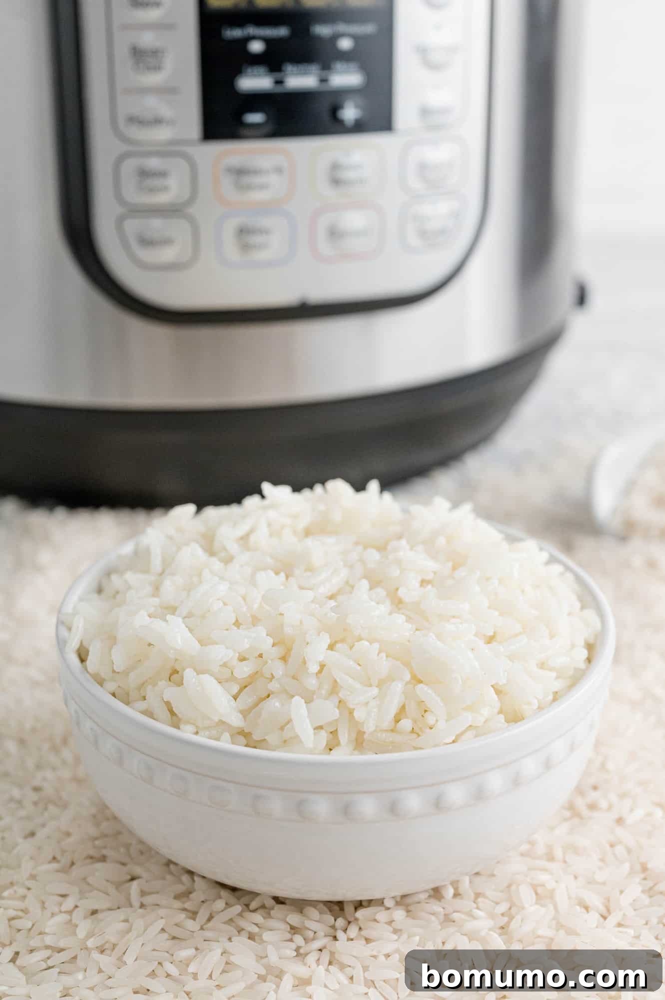 A bowl of rice prominently placed in front of an Instant Pot, symbolizing ease of preparation.