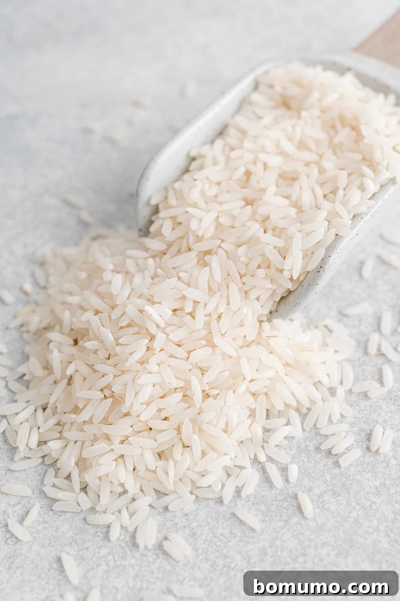 Uncooked long grain white rice in a wooden scoop, illustrating the raw ingredient.